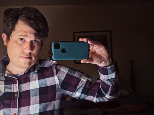 A selfie in the mirror of my bedroom at my parents' house. I'm grinning slightly, holding my phone, and wearing a purple, plaid, button-up shirt.
